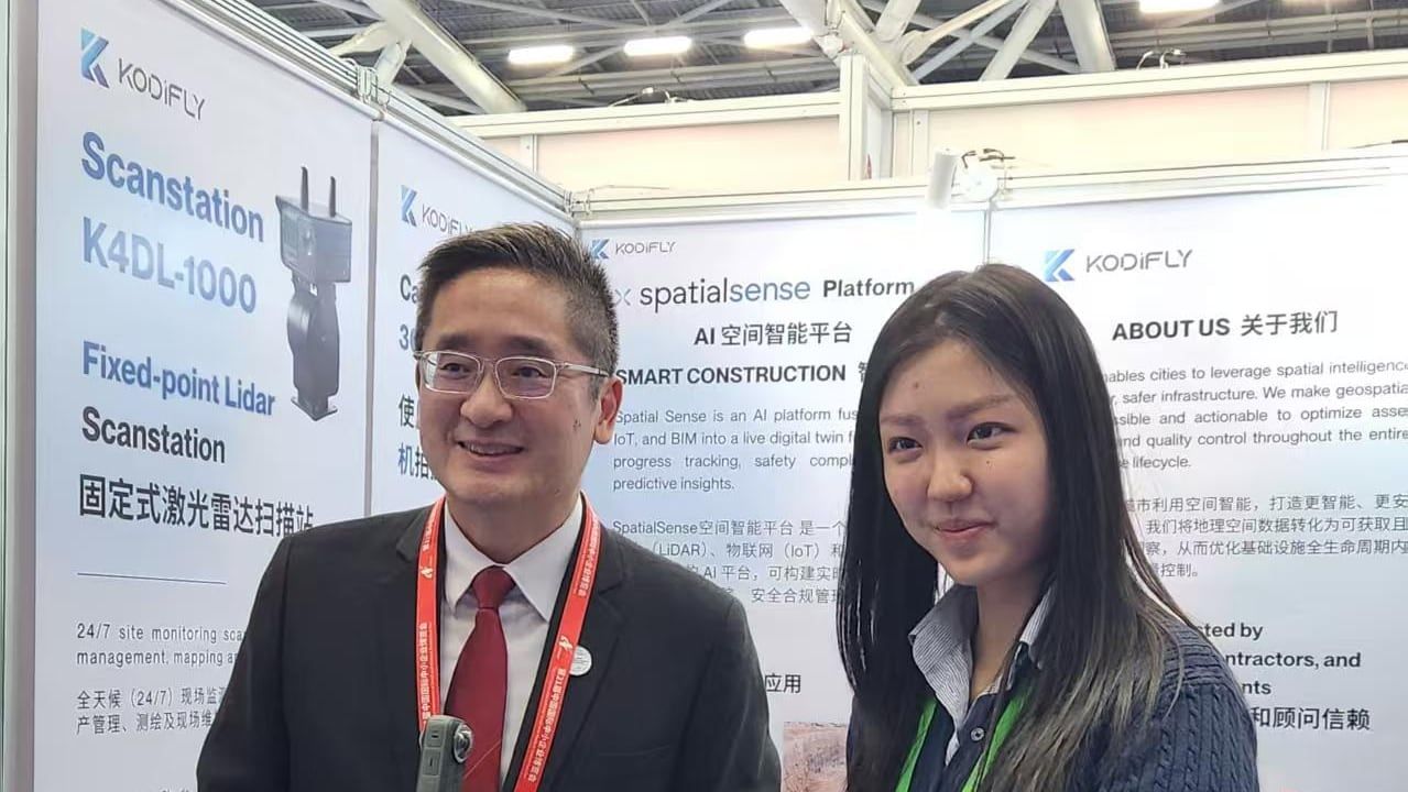 Kodifly staff at the company booth at the China International SME Fair, with a helmet camera and a laptop showing SpatialSense