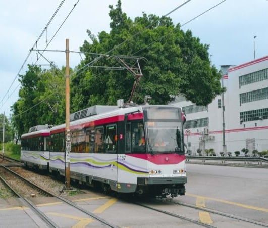 行走於路面路段的輕鐵列車,路軌旁有樹木及架空電纜